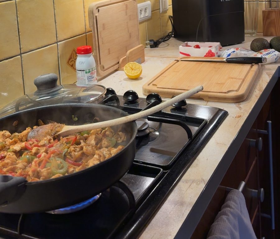 Une poêle de poulet aux poivrons sur le feu, plan de travail en cours